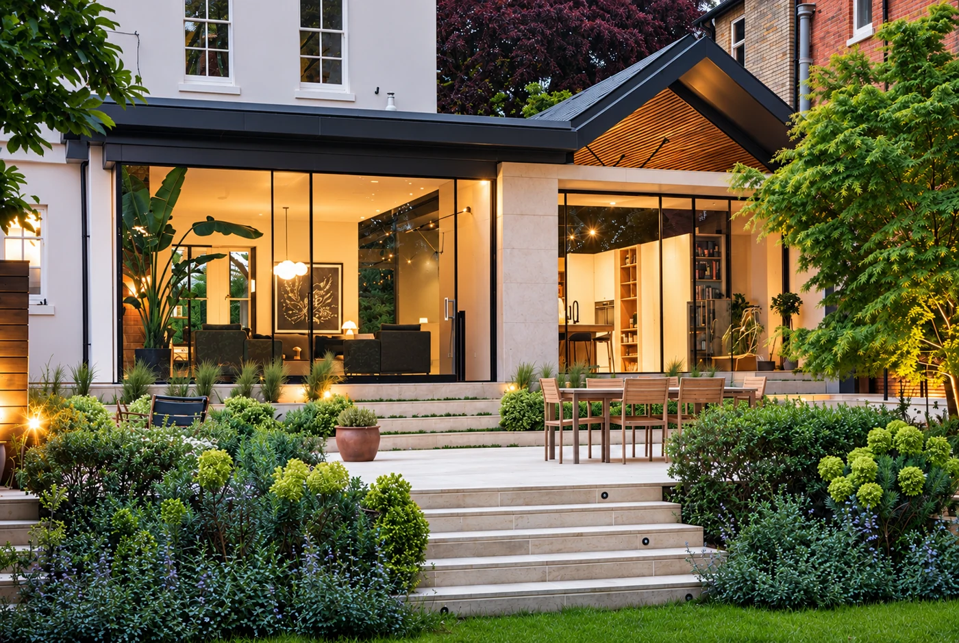 Contemporary glazed extension opening towards a landscaped garden at dusk